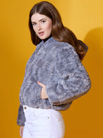A woman models the 98degreenorth Women’s Charcoal Grey Faux Fur Jacket against a solid yellow background.