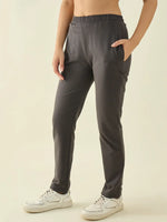 Woman in 98degreenorth Charcoal Regular Fit Trousers, hand in pocket, stands against a beige background.