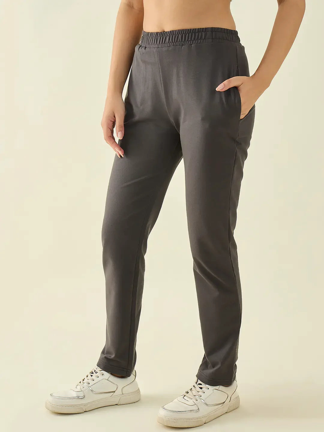 Woman in 98degreenorth Charcoal Regular Fit Trousers, hand in pocket, stands against a beige background.