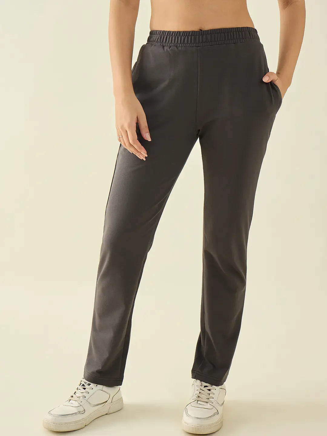 Model wears 98degreenorth Women’s Charcoal Regular Fit Cotton Stretchable Trousers with white sneakers.