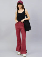 Woman in black tank top and 98degreenorth Cherry Mélange flared lounge pants, cap, sneakers, holding black tote bag.