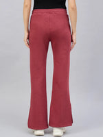Model in 98degreenorth Women’s Cherry Mélange Flared Lounge Pants and white shoes, shown from the back on gray.
