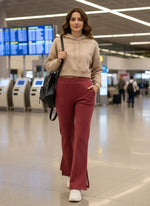 A woman in 98degreenorth Cherry Mélange Bootcut Sweatpants walks at the airport, black backpack in hand.