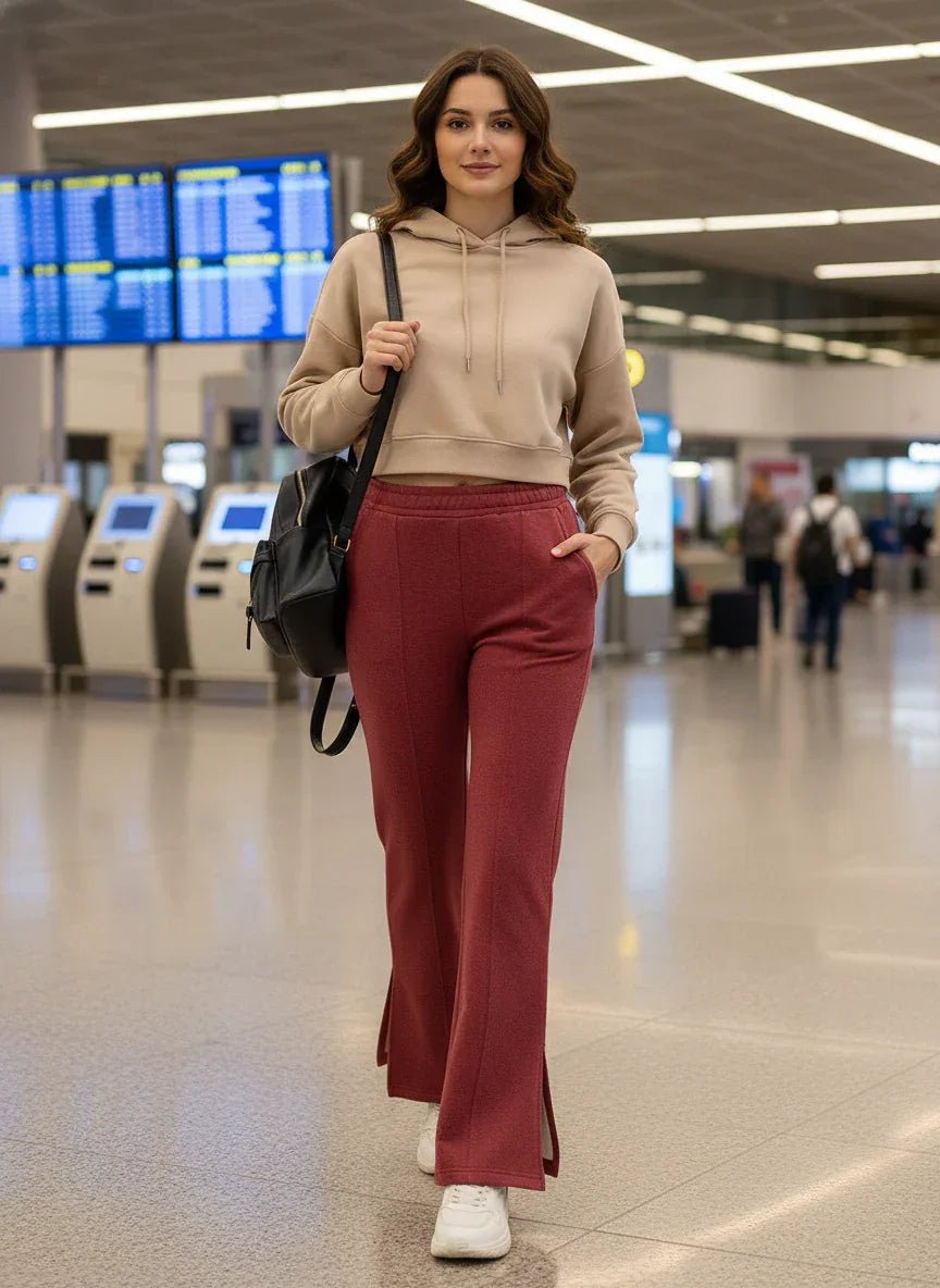 A woman in 98degreenorth Cherry Mélange Bootcut Sweatpants walks at the airport, black backpack in hand.