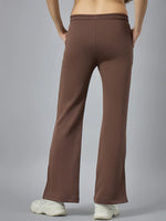 Model wears 98degreenorth Women’s Cocoa Brown Bootcut Sweatpants with white sneakers, hands in pockets, on gray backdrop.