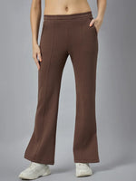 A person in 98degreenorth Women’s Cocoa Brown Bootcut Sweatpants, standing casually with one hand in a pocket.
