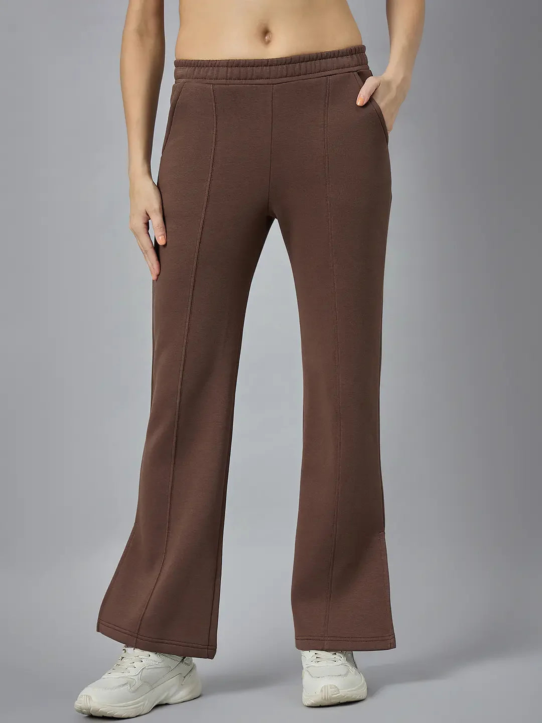 A person in 98degreenorth Women’s Cocoa Brown Bootcut Sweatpants, standing casually with one hand in a pocket.