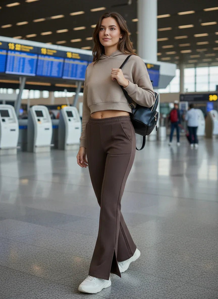 A woman in 98degreenorth’s Women’s Cocoa Brown Bootcut Sweatpants walks through the airport, flight boards behind her.