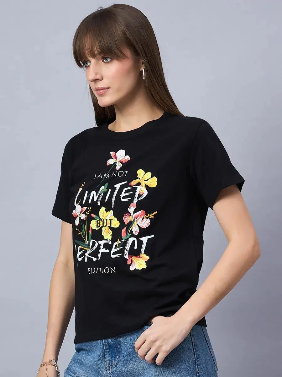 Woman wears the 98degreenorth Women’s Cotton Typography Graphic Tee with blue jeans, standing against a gray background.