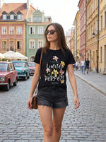 A woman in 98degreenorth’s Cotton Typography Graphic Tee and black shorts walks down a colorful cobblestone street.
