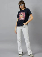 Woman in white sunglasses, 98degreenorth cotton typography graphic tee, white pants, and black-and-white sneakers.