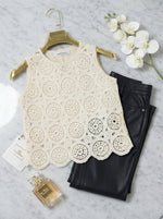 98degreenorth's beige crochet lace sleeveless crop top pairs perfectly with black pants, perfume, and a white orchid.