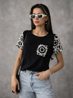 Woman wears 98degreenorth’s Women's Crochet Sleeve Contrast Top in black with lace detail, white sunglasses, and blue jeans.