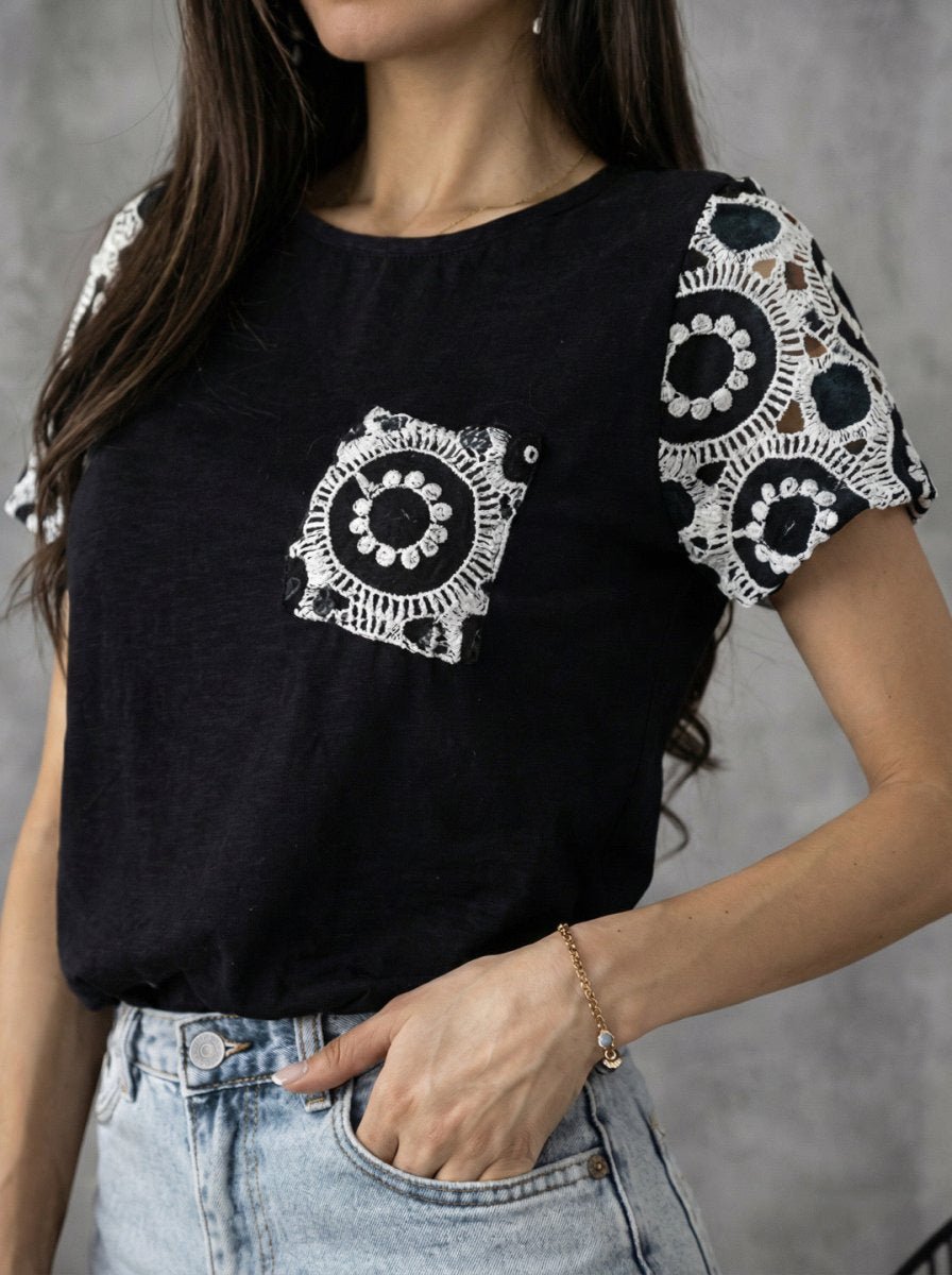 Woman in 98degreenorth Women's Crochet Sleeve Contrast Top - Black, paired with light blue jeans.
