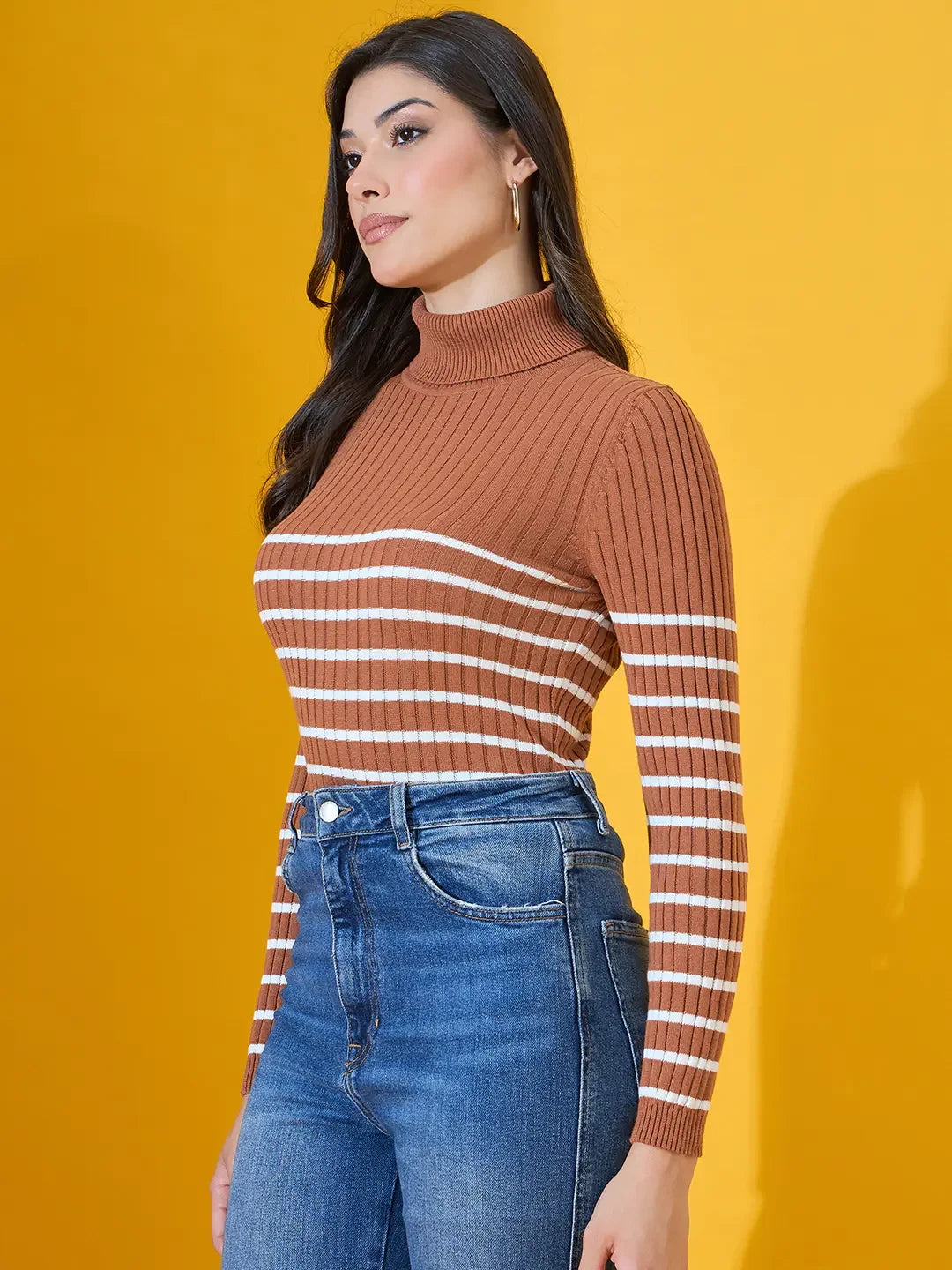 Woman in a 98degreenorth Dark Camel Ribbed Turtleneck Sweater stands against a bright yellow background.