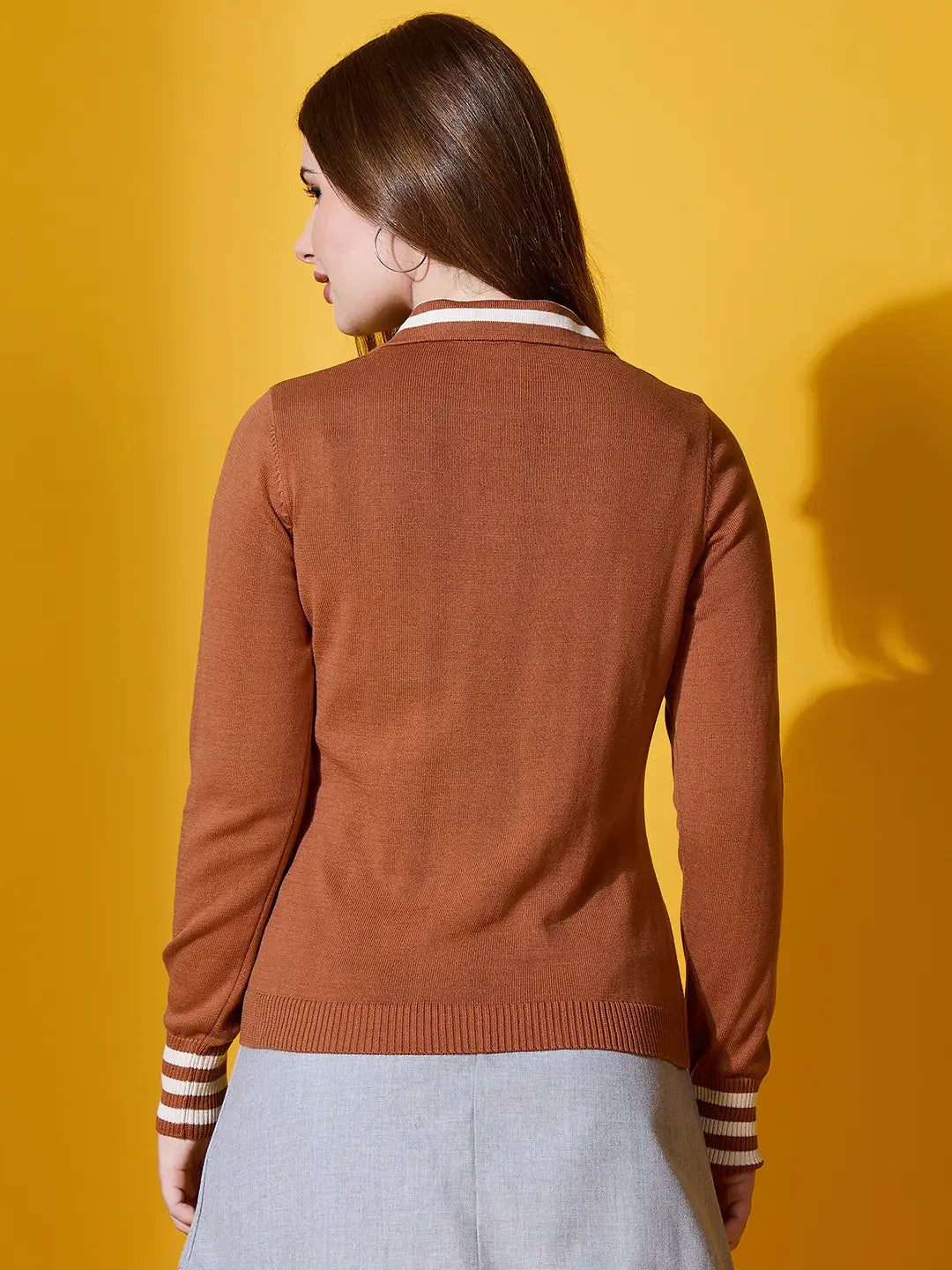 Woman wearing 98degreenorth’s Dark Camel Striped-Collar Knit Sweater, pictured from behind with a grey skirt.