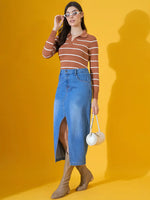 Woman wears 98degreenorth dark camel striped collared sweater, denim skirt, tan boots, and white sunglasses on yellow.