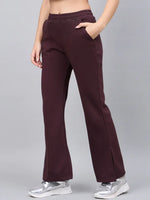 Woman models 98degreenorth Dark Wine Bootcut Sweatpants with side slit, styled with silver sneakers on a grey backdrop.