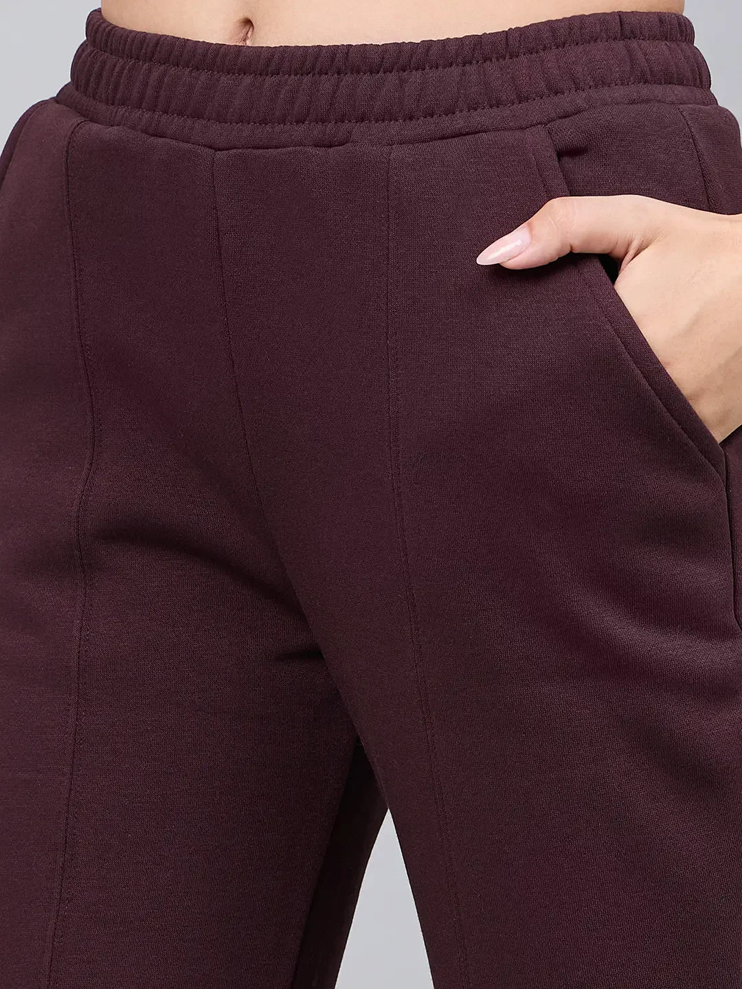 Close-up of 98degreenorth Women’s Dark Wine Bootcut Sweatpants with side slit, hand in pocket and light pink nails showing.