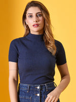 Woman with wavy light brown hair in a 98degreenorth denim blue ribbed turtle neck sweater, against a yellow background.