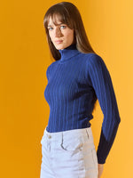 Woman wears 98degreenorth denim blue ribbed turtleneck slim fit sweater, cozy winter wear, against a yellow background.
