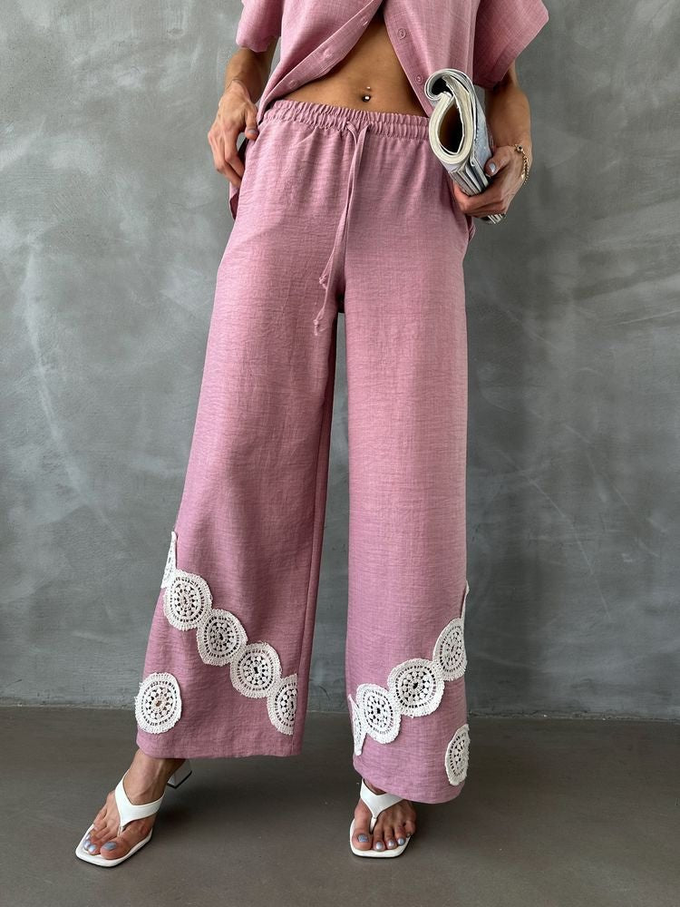 Model in 98degreenorth's dusty pink wide leg linen pants with crochet detail, white sandals, and a magazine.