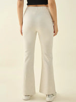 A person wears 98degreenorth Women’s Ecru Flared Bootcut Trousers, white sneakers, and a black top, shown from the back.