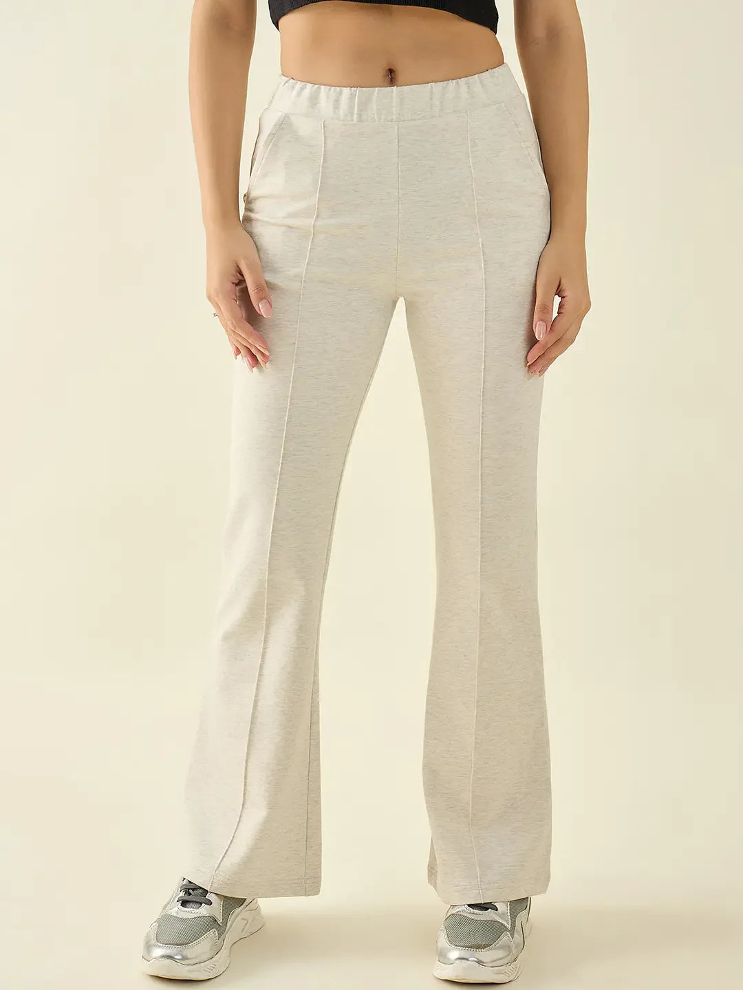 Woman in 98degreenorth Women’s Ecru Flared Bootcut Cotton Stretchable Trousers, black crop top, gray sneakers.