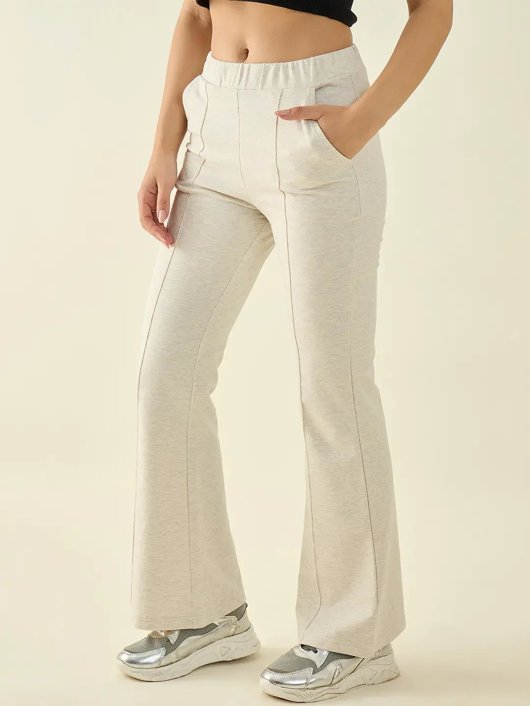 Woman wearing 98degreenorth Women’s Ecru Flared Bootcut Cotton Stretchable Trousers with silver sneakers and a cropped top.