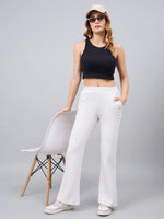 Woman in a black crop top, 98degreenorth Women’s Ecru Flared Bootcut Sweatpants, beige cap, and sunglasses by a white chair.