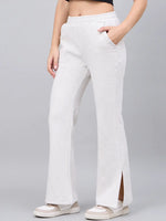 Someone in 98degreenorth’s ecru flared bootcut side-slit lounge pants, white sneakers, and a black top.