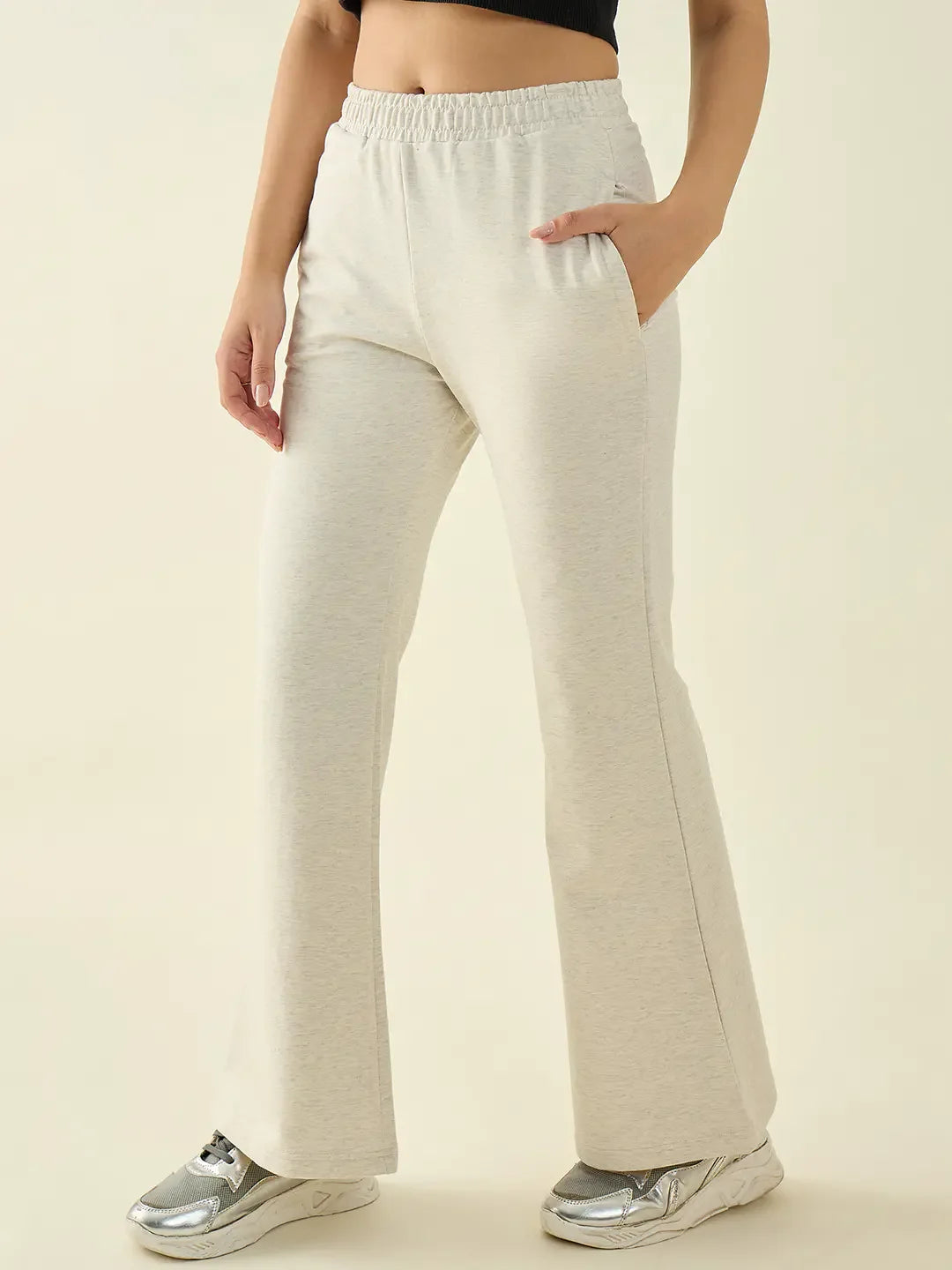 Woman wearing 98degreenorth Women’s Ecru Flared Fit Bootcut Cotton Stretchable Trousers with a black crop top and silver sneakers.