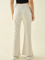Model in 98degreenorth Women’s Ecru Flared Fit Bootcut Cotton Stretchable Trousers and white sneakers, back view.