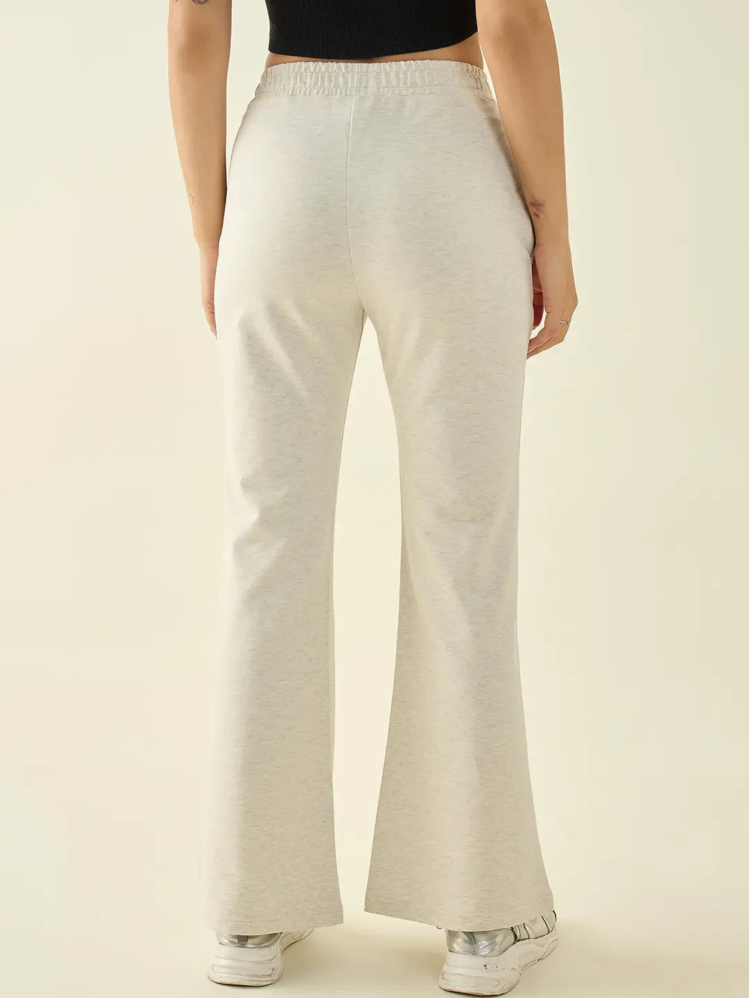 Model in 98degreenorth Women’s Ecru Flared Fit Bootcut Cotton Stretchable Trousers and white sneakers, back view.