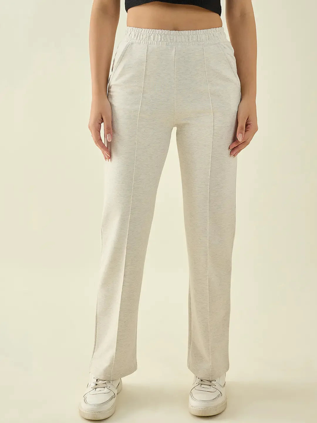 Woman in 98degreenorth Ecru Straight Fit Cotton Stretchable Trousers and white sneakers, against a plain background.