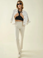 Woman in sunglasses, crop top, white jacket, and 98degreenorth ecru stretchable trousers poses confidently.