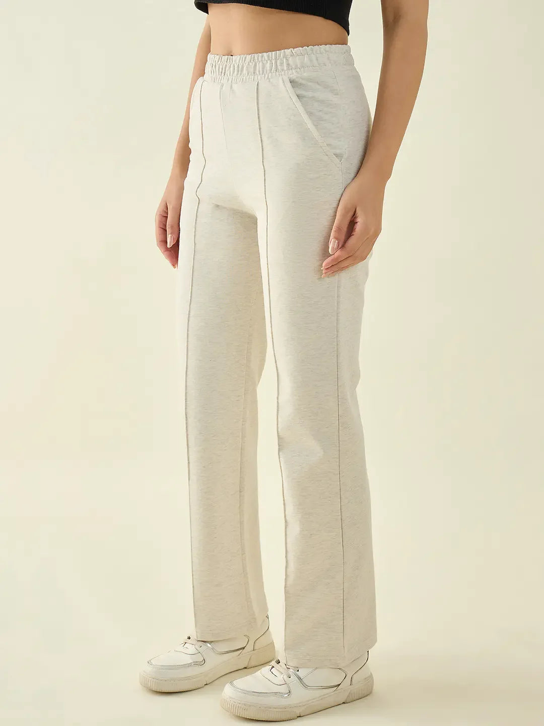 Woman in 98degreenorth Ecru Straight Fit Cotton Stretchable Trousers and black crop top stands against a plain background.