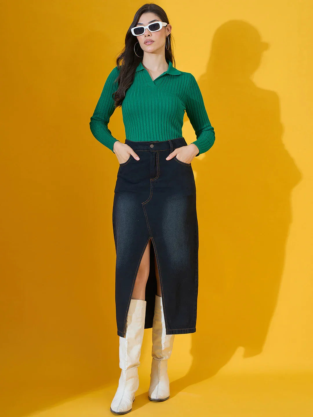 Woman in 98degreenorth’s Emerald Green Ribbed Collar Neck Sweater, dark denim skirt, white boots & sunglasses.