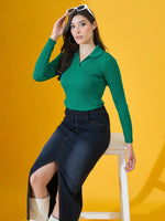 Woman wears 98degreenorth’s Emerald Green Ribbed Collar Neck Sweater with denim skirt, seated against a yellow backdrop.