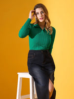 Woman in a 98degreenorth emerald green ribbed collar sweater sits on a stool against yellow, touching her hair.