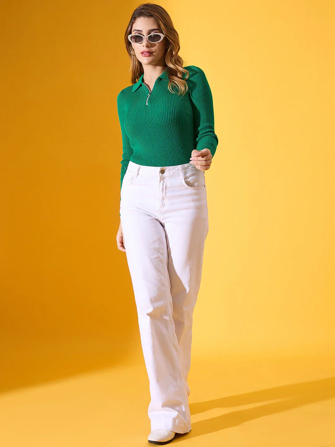 Woman in a 98degreenorth emerald green ribbed collar zipper sweater stands against a bright yellow background.