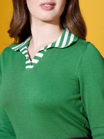Woman wears 98degreenorth’s fern green striped collar knit sweater, posing against a yellow background.