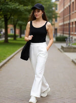 Woman in black tank top and 98degreenorth Off White Flared Bootcut Fleece Sweatpants walks on a paved path.