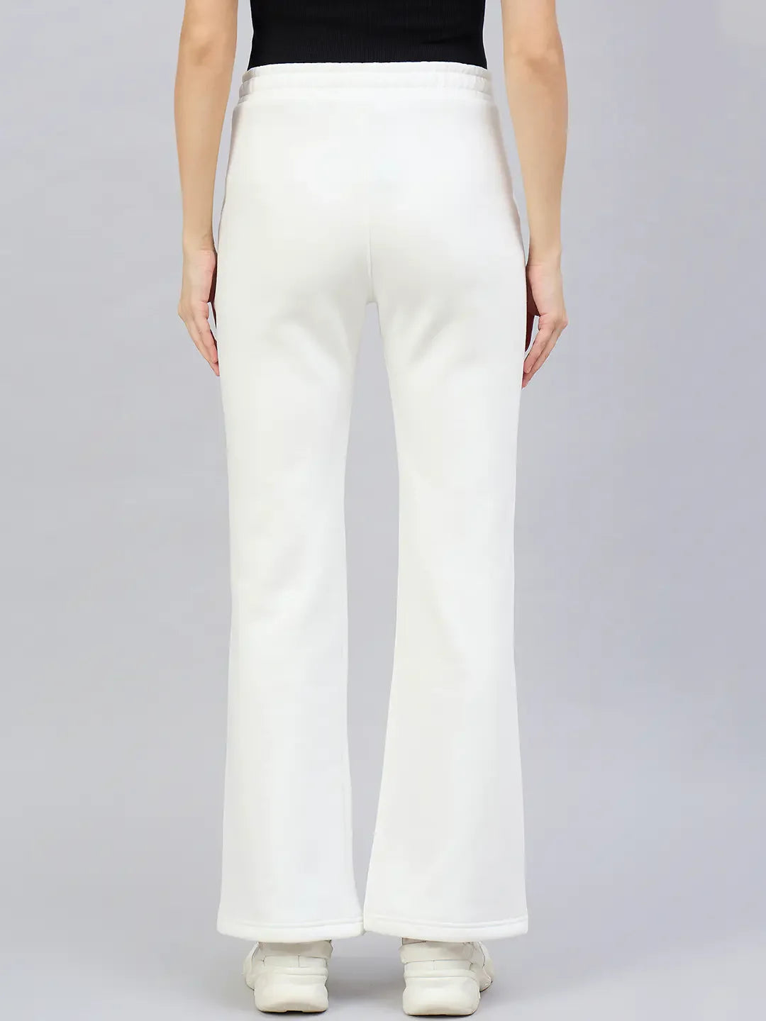 Model wears 98degreenorth Women’s Flared Bootcut Fleece Sweatpants in Off White, shown from the back against gray.