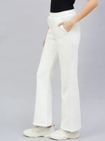 Person models 98degreenorth Women’s Flared Bootcut Fleece Sweatpants in Off White with a black top and white sneakers.