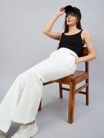 Woman in a black tank top and black cap wears 98degreenorth’s off white flared bootcut fleece sweatpants.