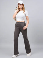 Woman wears 98degreenorth’s olive flared bootcut fleece sweatpants, white crop top, and cap against a gray background.