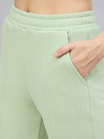 Close-up of a person wearing 98degreenorth Women’s Flared Bootcut Fleece Sweatpants in Pista with a hand in the pocket.