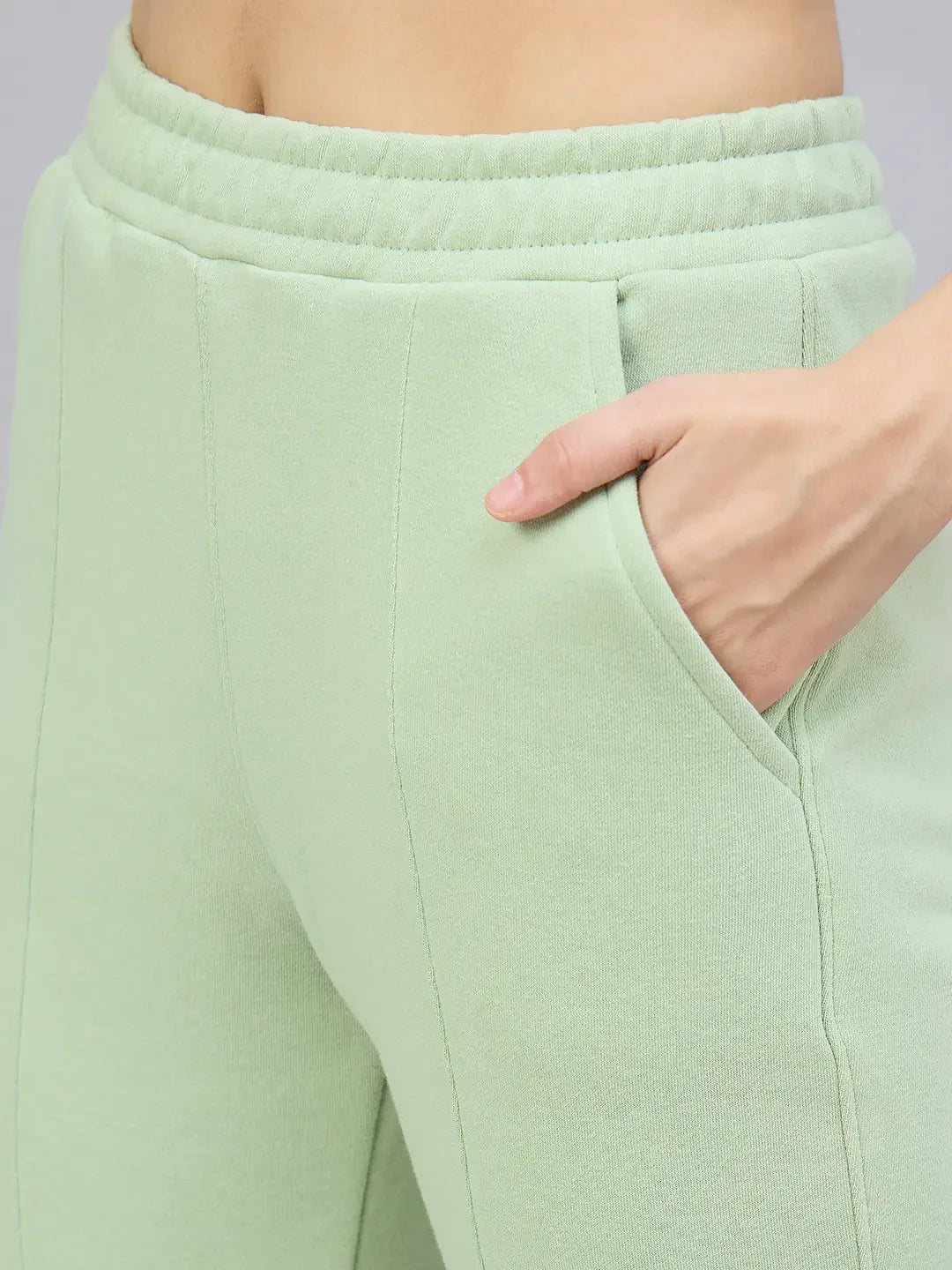 Close-up of a person wearing 98degreenorth Women’s Flared Bootcut Fleece Sweatpants in Pista with a hand in the pocket.