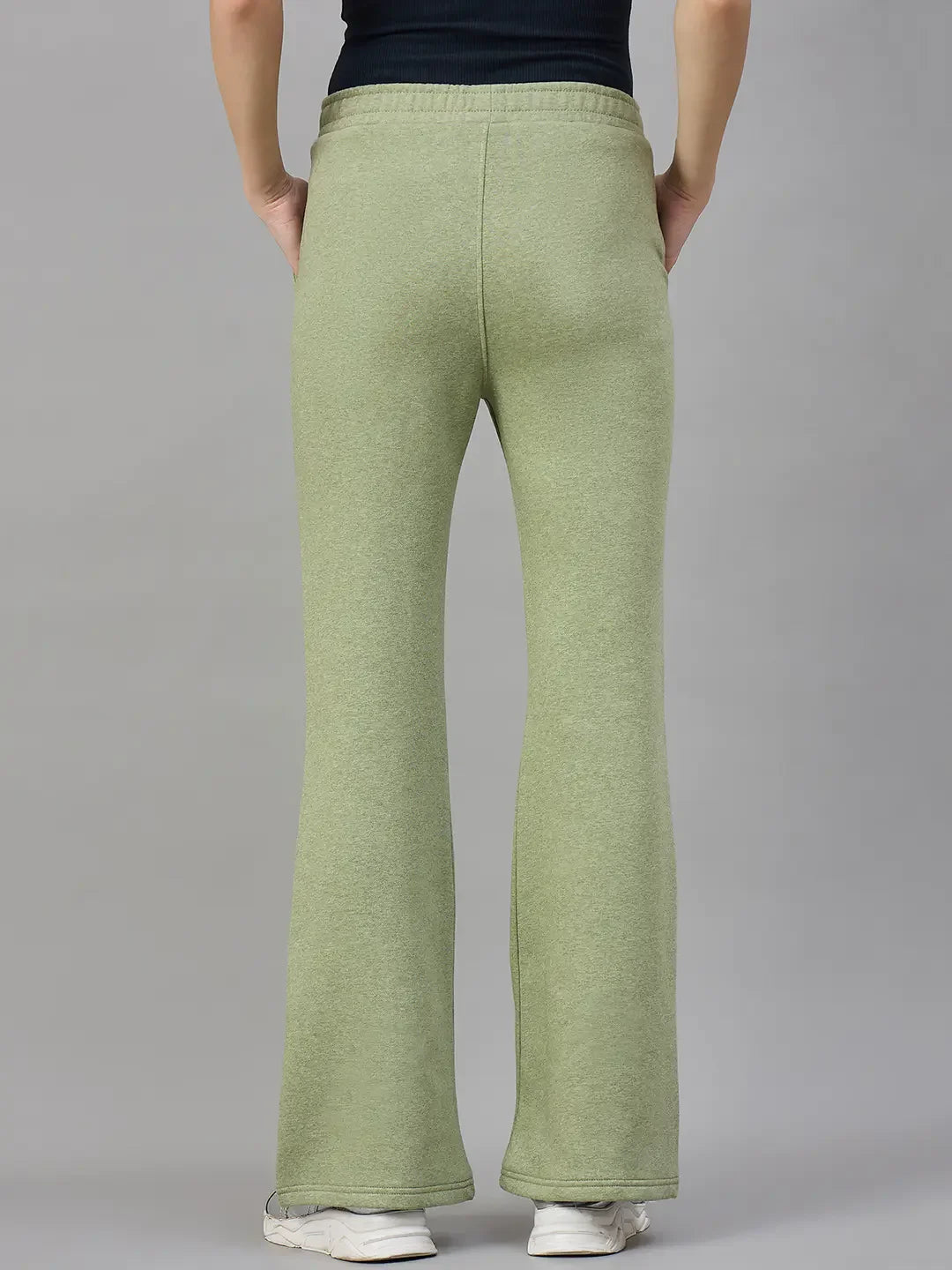 Model wears 98degreenorth Women’s Flared Bootcut Fleece Sweatpants in Pista Melange with a black top and white shoes, back view.